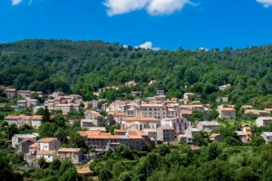 Vue du centre du village de Bastelica entouré de maisons en pierre et de maquis