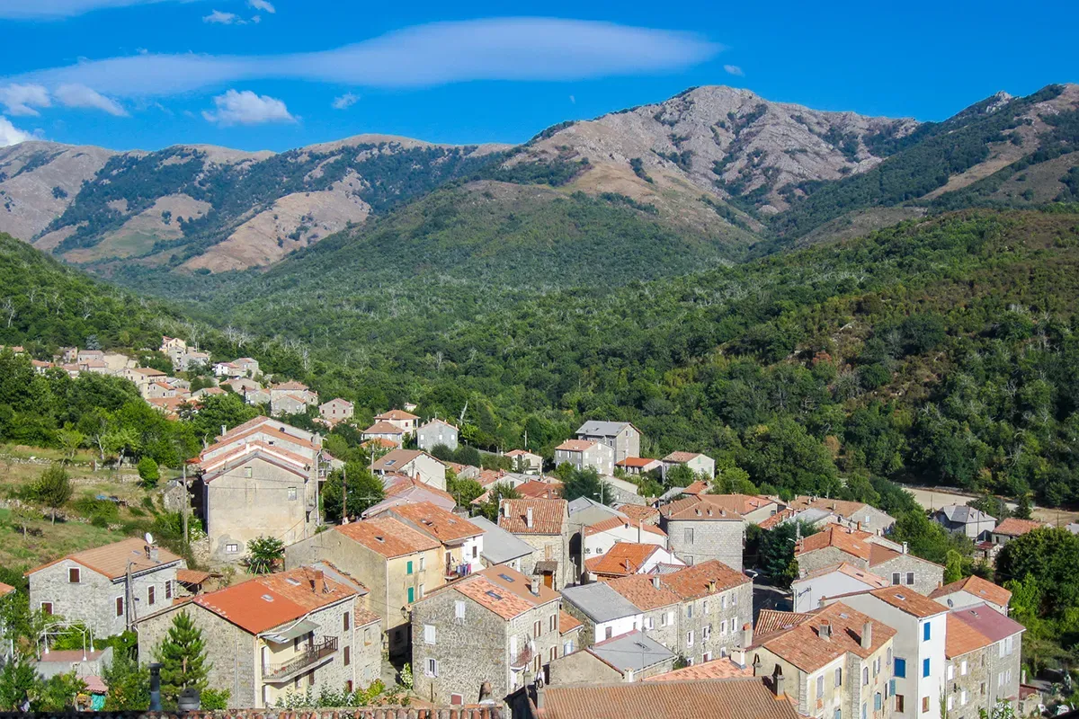 Vue du village de Bastelica entouré de montagnes en été